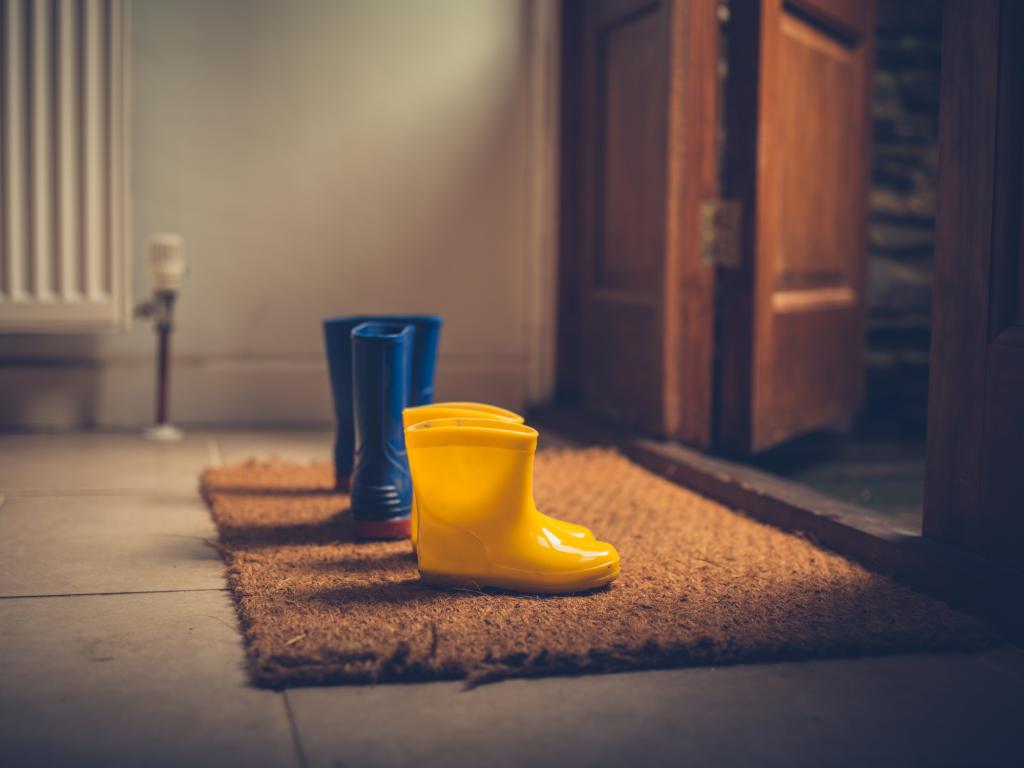 A photograph of an adult and child pair of wellies on a door welcome mat