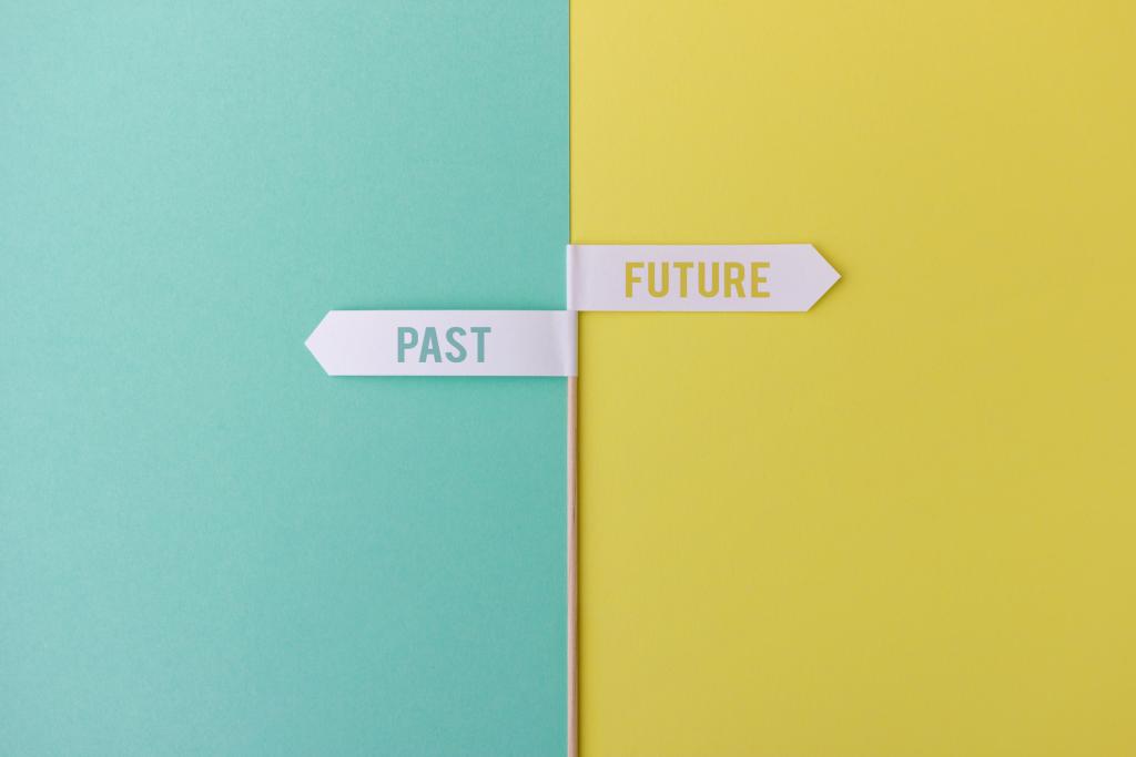 Wood stick with small white flags on yellow and blue background showing past and future