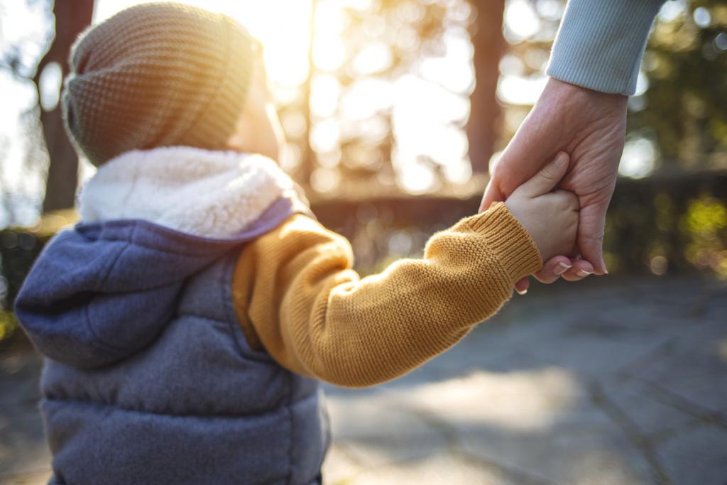 Close up of parent and a child hands at sunset.