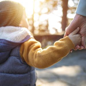 Close up of parent and a child hands at sunset.