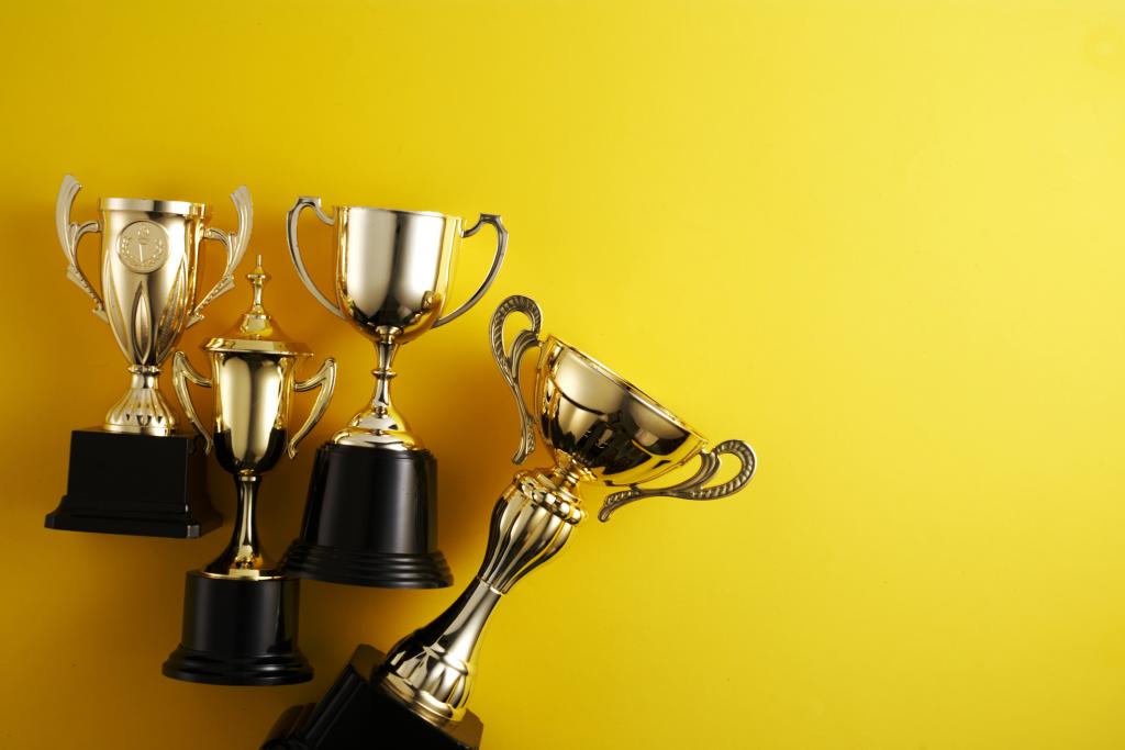 four gold trophies laying against yellow background