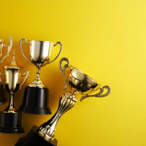 four gold trophies laying against yellow background