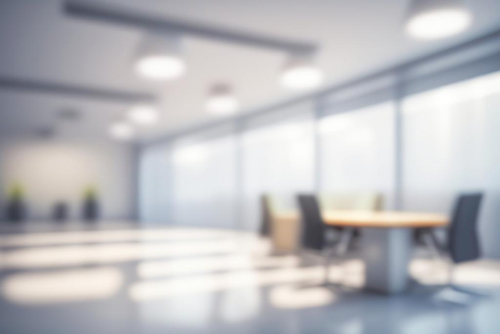 Blurred photograph of a light modern office interior with panoramic windows and beautiful lighting.