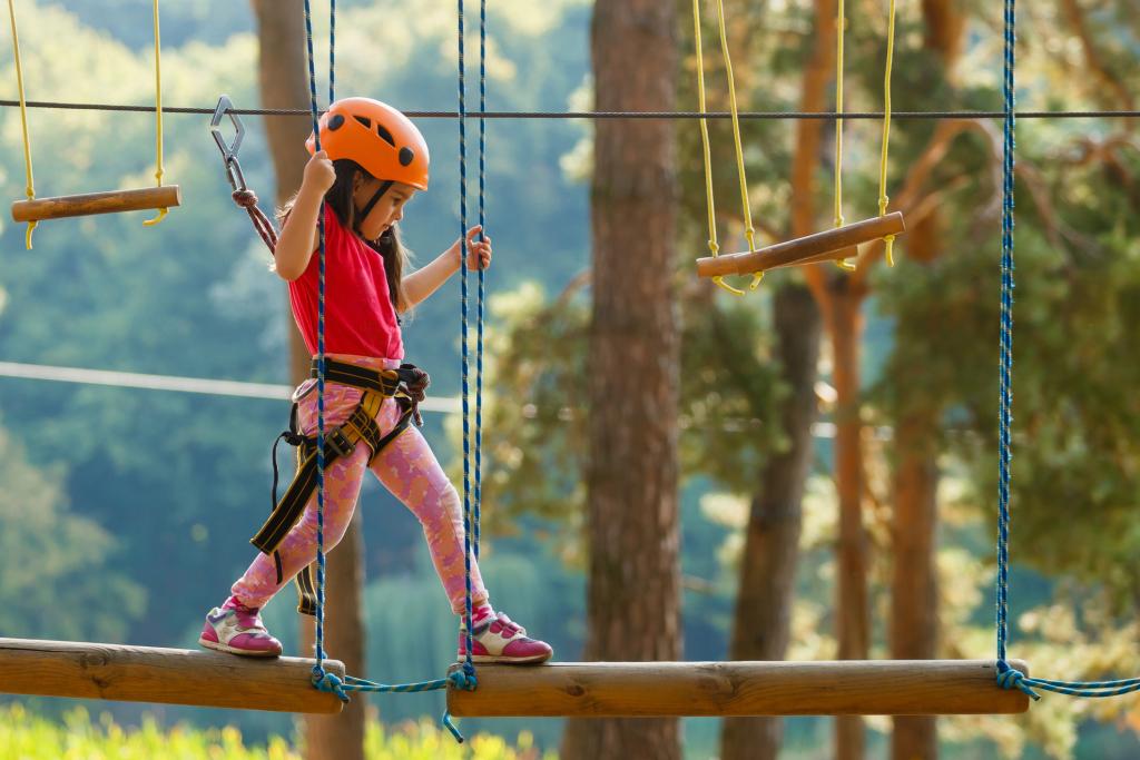 Photograph of a young girl walking on a rope bridge in an adventure rope park.