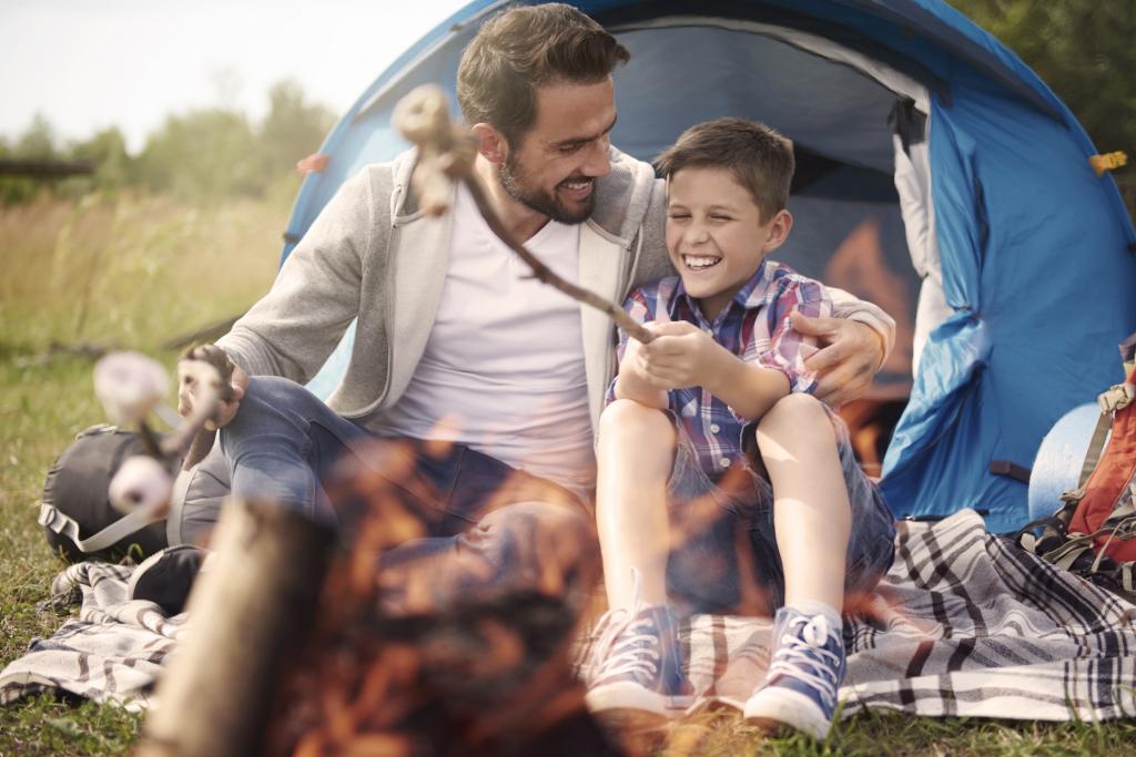 Father and son cook marshmallows over a bonfire while camping