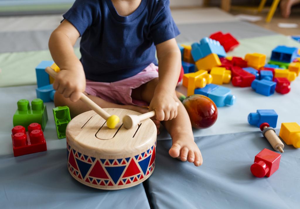 Little boy playing wooden toy drum by himself