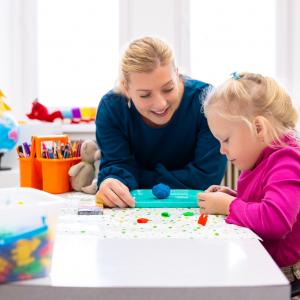 Toddler girl with parent playing with sensory toys.