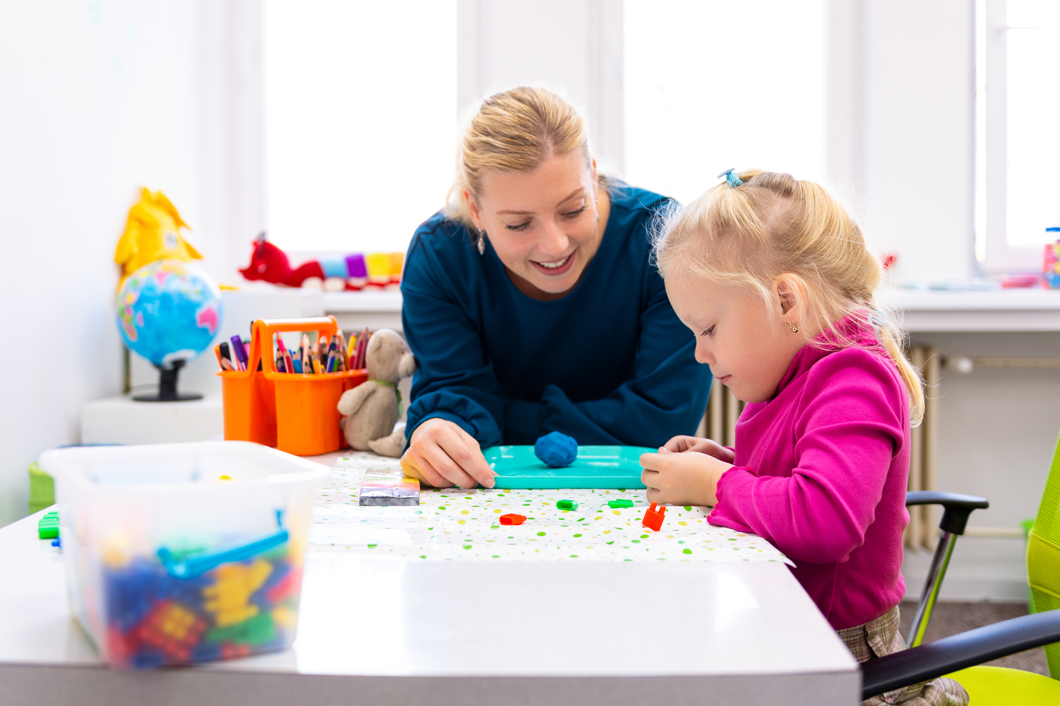 Toddler girl with parent playing with sensory toys.