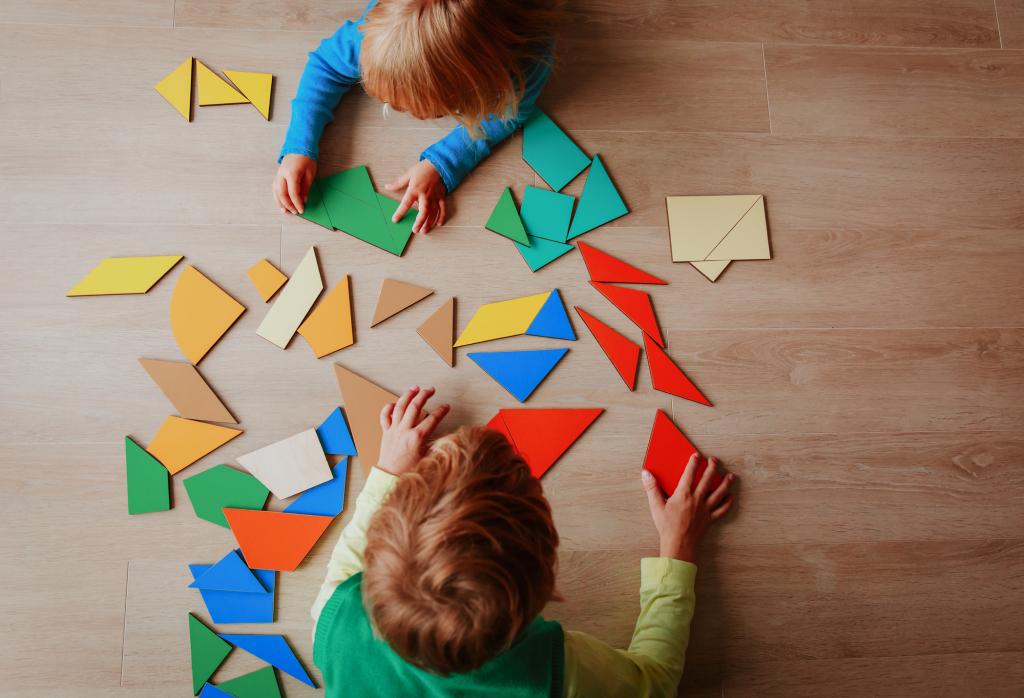 Two young children playing with puzzle shapes seen from above