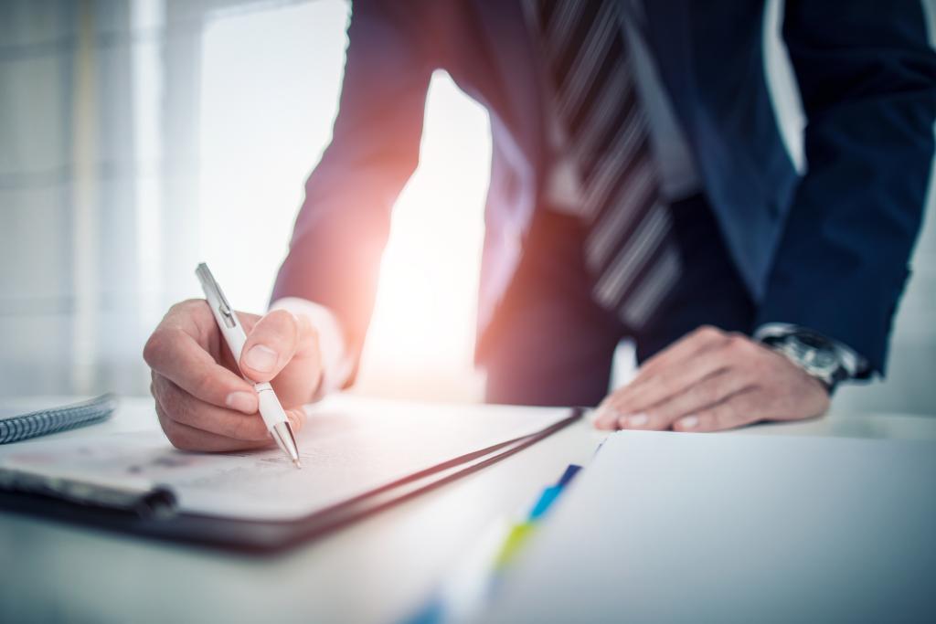 Man reviewing information on clipboard over his desk