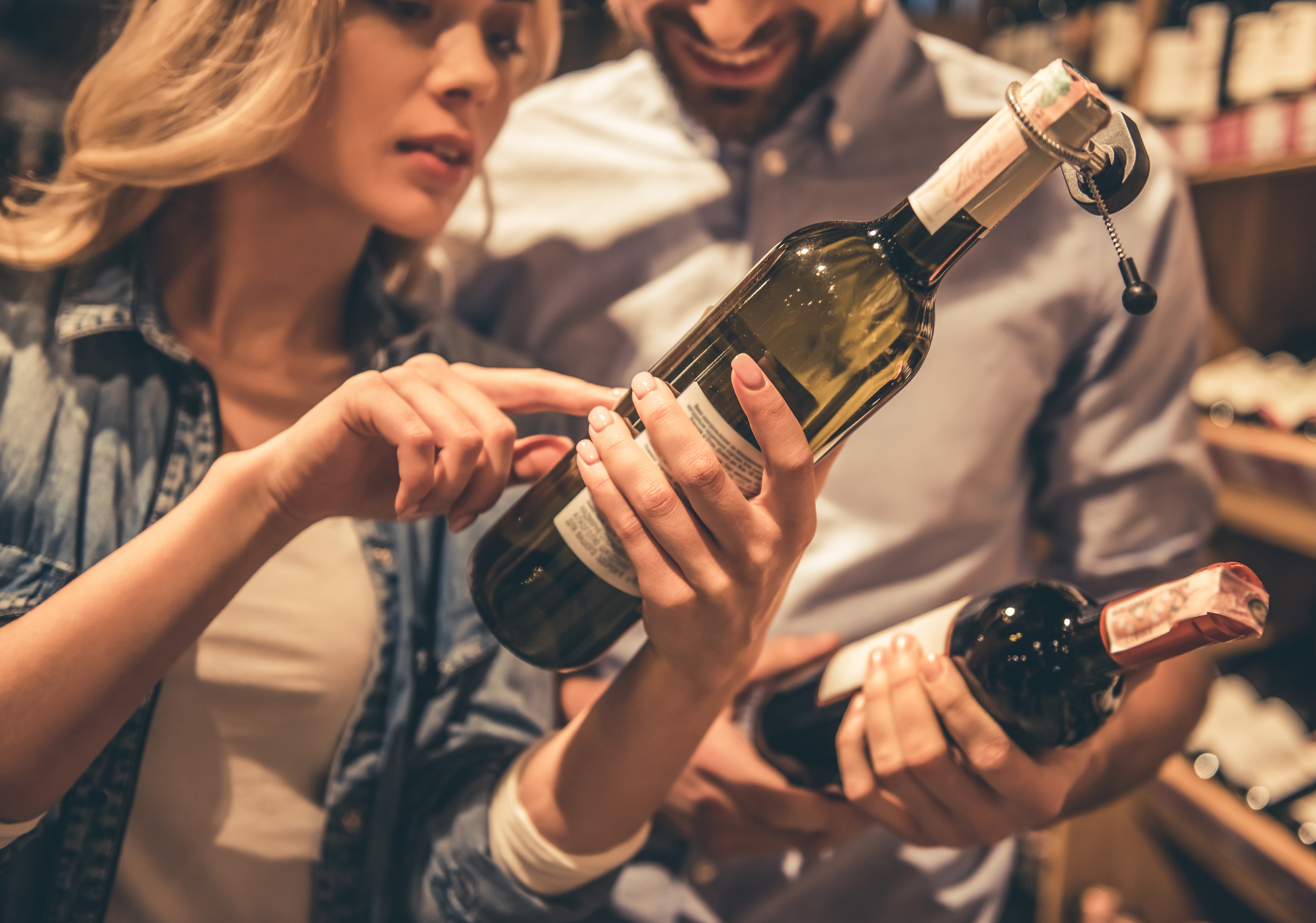 Couple at the supermarket checking a wine bottle label