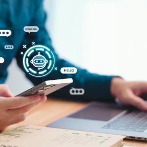 Business person using generative AI in the workplace on their phone and laptop