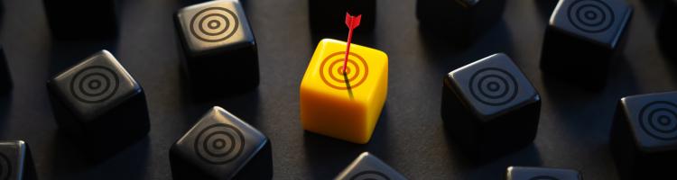 An arrow landing on a yellow target surrounded by black targets