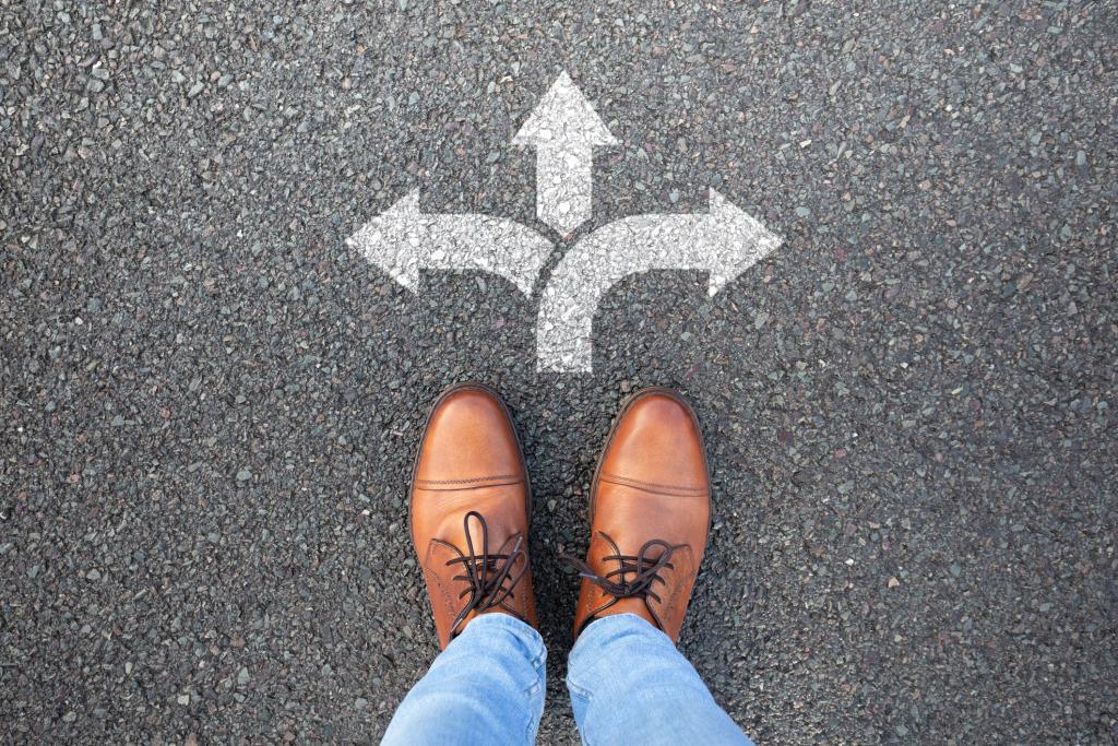Business owner standing at a crossroads choosing employee ownership as a succession path.
