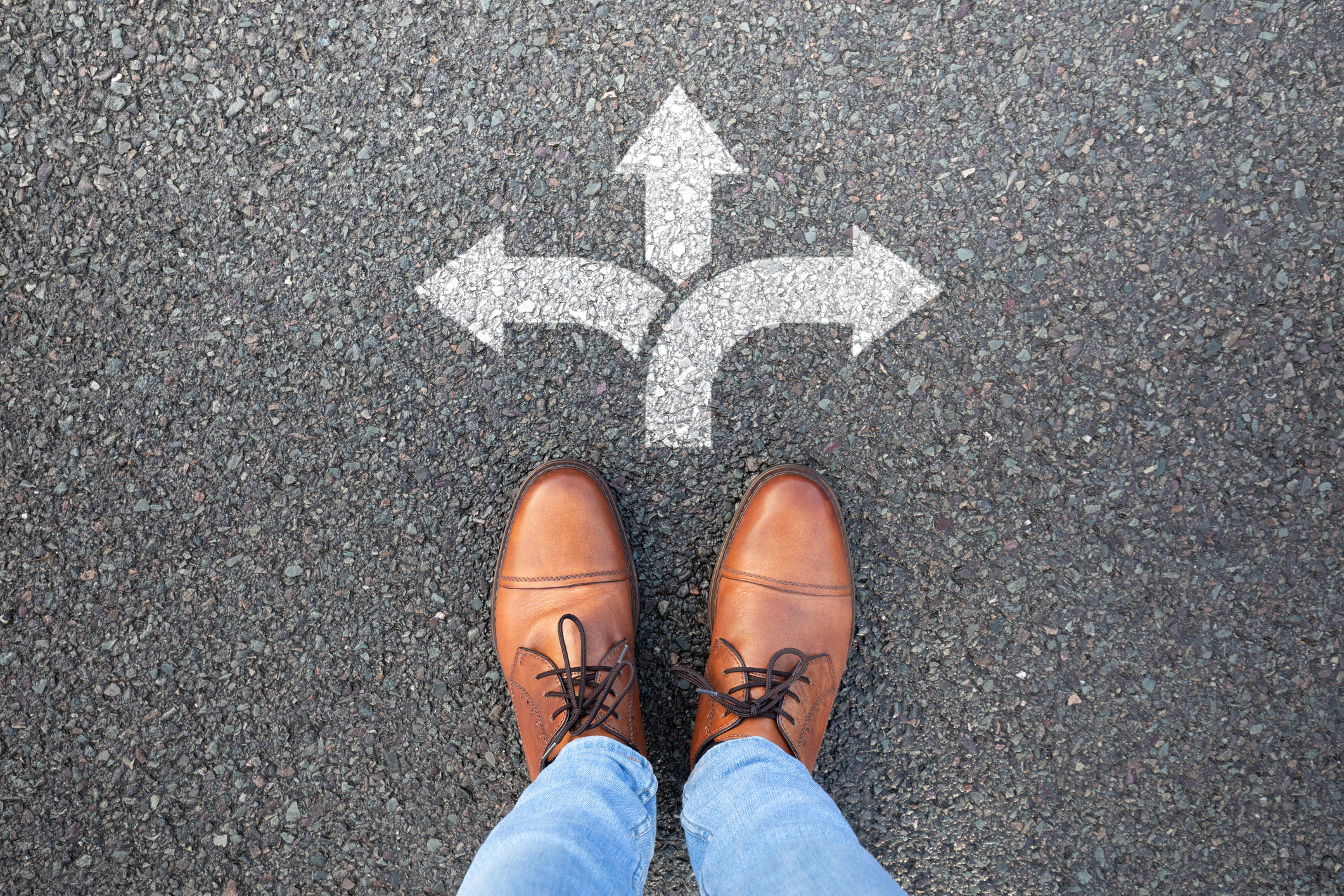 Business owner standing at a crossroads choosing employee ownership as a succession path.