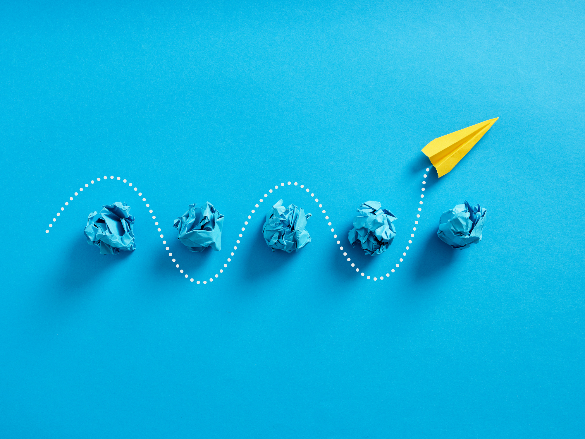 Paper plane passes through the crumpled paper balls.