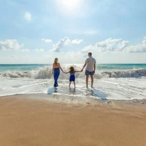 Family on beach holding hands, mother, father, child
