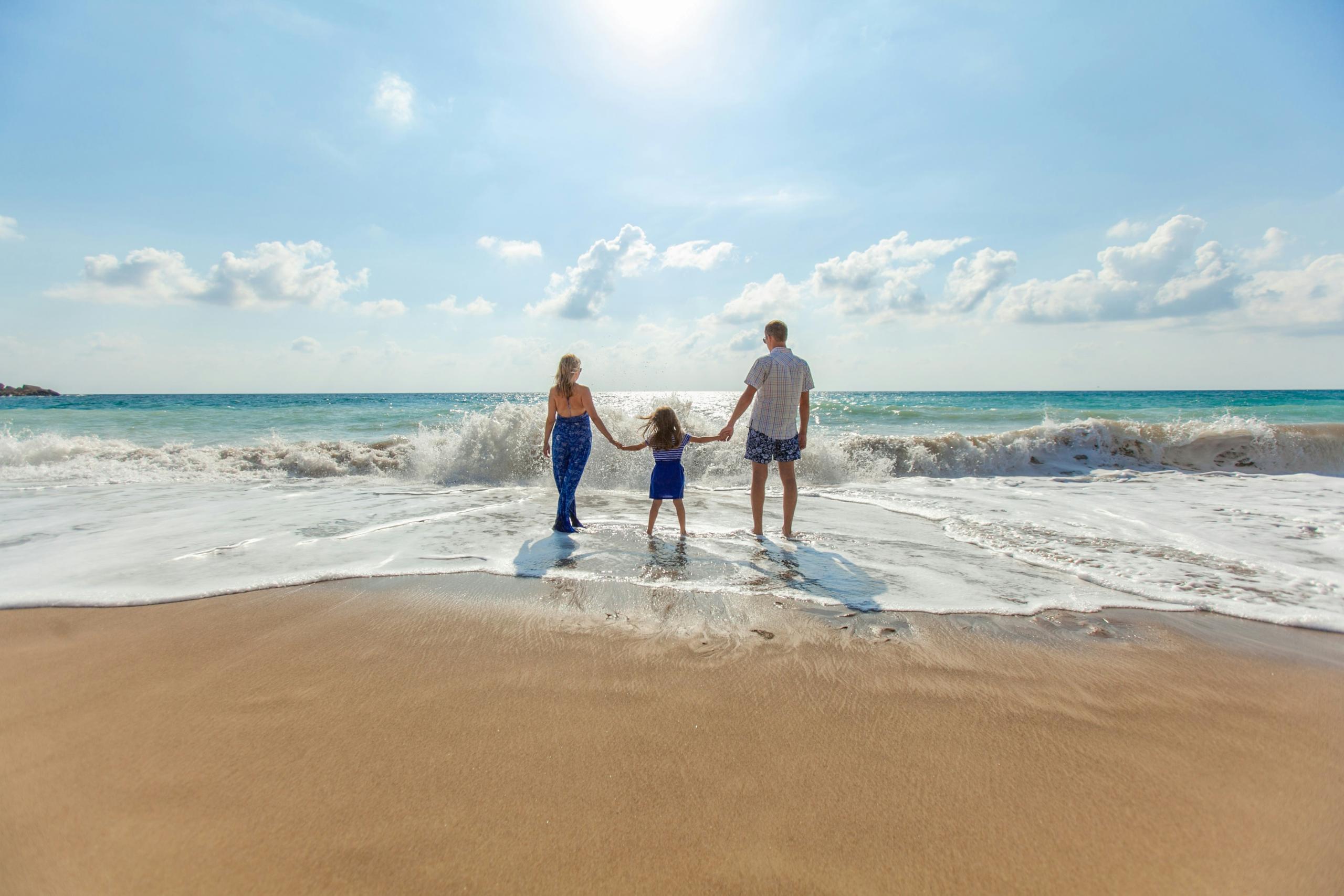 Family on beach holding hands, mother, father, child
